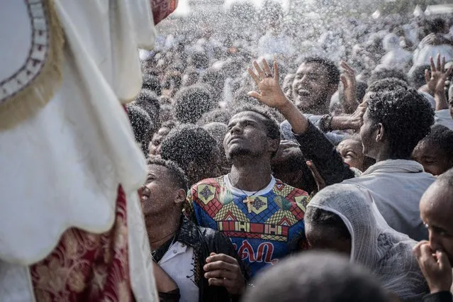 Ethiopian Orthodox worshippers get holy water sprayed on their faces during the celebration of the Ethiopian Epiphany in Addis Ababa, Ethiopia on January 20, 2024. Timkat is the Ethiopian Orthodox Christian festival which celebrates the baptism of Jesus in the Jordan river. (Photo by Amanuel Sileshi/AFP Photo)