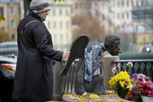 A woman touches the sculpture “Sad Angel”, a memorial for St. Petersburg's medical workers who died from coronavirus during their work in St. Petersburg, Russia, Friday, October 15, 2021. Russia's daily tolls of coronavirus infections and deaths have surged to another record in a quickly mounting figure that has put a severe strain on the country's health care system. The record for daily COVID-19 deaths in Russia has been broken repeatedly over the past few weeks as fatalities steadily approach 1,000 in a single day. (Photo by Dmitri Lovetsky/AP Photo)