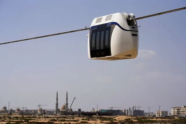 A small, four-seat pod made by uSky glides above the sands of a test track in Sharjah, United Arab Emirates, Thursday, October 28, 2021. The futuristic transit solution is being promoted by a Belarusian firm that hopes to secure contracts here in the near future. However, uSky has ties back to a Belarusian investment firm called SkyWay that has seen multiple nations in Europe and elsewhere issue warnings to investors that they “may be involved in a scam”. (Photo by Jon Gambrell/AP Photo)