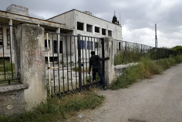 A Sudanese immigrant walks climbs through a gate at a deserted textile factory in the western Greek town of Patras April 28, 2015. (Photo by Yannis Behrakis/Reuters)