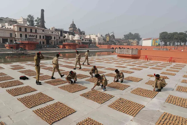 National Cadet Corps cadets arrange earthen lamps on the banks of Saryu river in Ayodhya , India, Tuesday, November 2, 2021. Hundreds of thousands of lamps are to be illuminated on Deepotsav celebrations on the eve of Diwali. (Photo by Rajesh Kumar Singh/AP Photo)