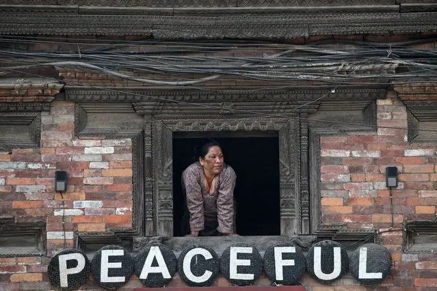 A woman looks out from a window in Bhaktapur on March 14, 2024. (Photo by Prakash Mathema/AFP Photo)