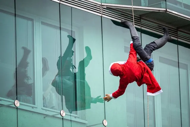 A climber disguised as Santa Claus goes down a paediatric clinic building in Ljubljana on December 22, 2021. (Photo by Jure Makovec/AFP Photo)