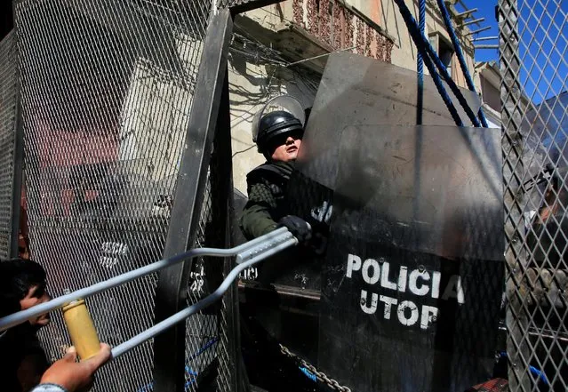 A riot policeman tries to take a crutch from a demonstrator, during a protest by people with physical disabilities demanding the government to increase their monthly disability subsidy, in La Paz, Bolivia, April 29, 2016. (Photo by David Mercado/Reuters)