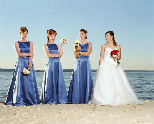 Bride with bridesmaids holding bouquet of roses (Rosa sp.) on beach. (Photo by Greg Ceo/Getty Images)