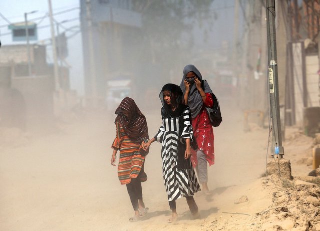 Girls cover their heads as they walk on a street near a landfill site on a hot summer day during a heatwave in New Delhi, India, oon May 27, 2024. (Photo by Anushree Fadnavis/Reuters)