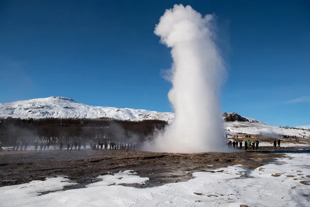 Tourists watch the geyser Strokkur erupt next to the originally named Geysir on March 27, 2017 near Blaskogabyggo, Iceland. Iceland's economy has been booming, after an economic crash and collapse of its banking system in 2008, gross domestic produce has surged in recent years helped by floods of tourists visiting the country. Data from the Icelandic statistics office has shown that Iceland's GDP jumped 11.3 per cent in the final quarter of 2016 from the same period a year before, the fastest pace of growth since before the financial crisis. (Photo by Chris J Ratcliffe/Getty Images)