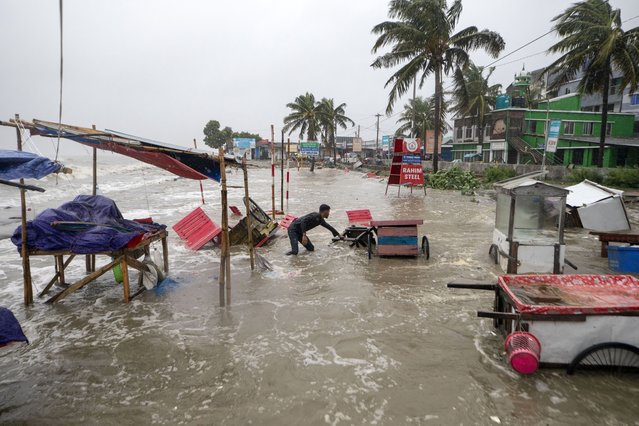 A man salvages a cart and other material as water flows on to the Kuakata beach on the coast of Bay of Bengal caused by the advancing Cyclone Remal in Barisal, Bangladesh, Sunday, May 26, 2024. (Photo by Abdul Goni/AP Photo)