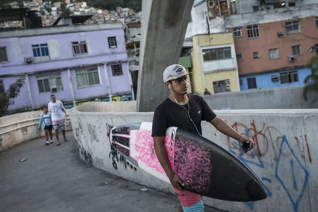 Cristiano Gomes “Xuxu” leaves Rocinha slum on his way to Sao Conrado beach in Rio de Janeiro, Brazil, Thursday, May 21, 2015. Before he learned how to surf at the school, his “life was pretty bad”, he says. He would juggle for spare change from motorists at the busy highway intersection at the base of the Rocinha shantytown. (Photo by Felipe Dana/AP Photo)