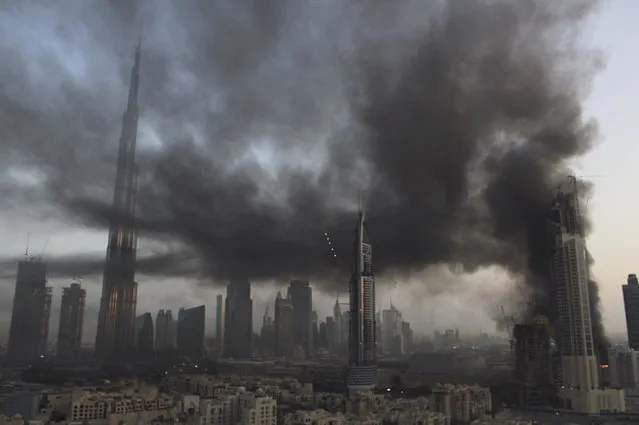 Smoke rises from a fire at a construction site next to Dubai Mall in Dubai, United Arab Emirates, Sunday, April 2, 2017. A large fire broke out early Sunday at a construction site near Dubai’s largest shopping mall, sending thick gray smoke billowing over the heart of the city. (Photo by Anthea Ayache via AP Photo)