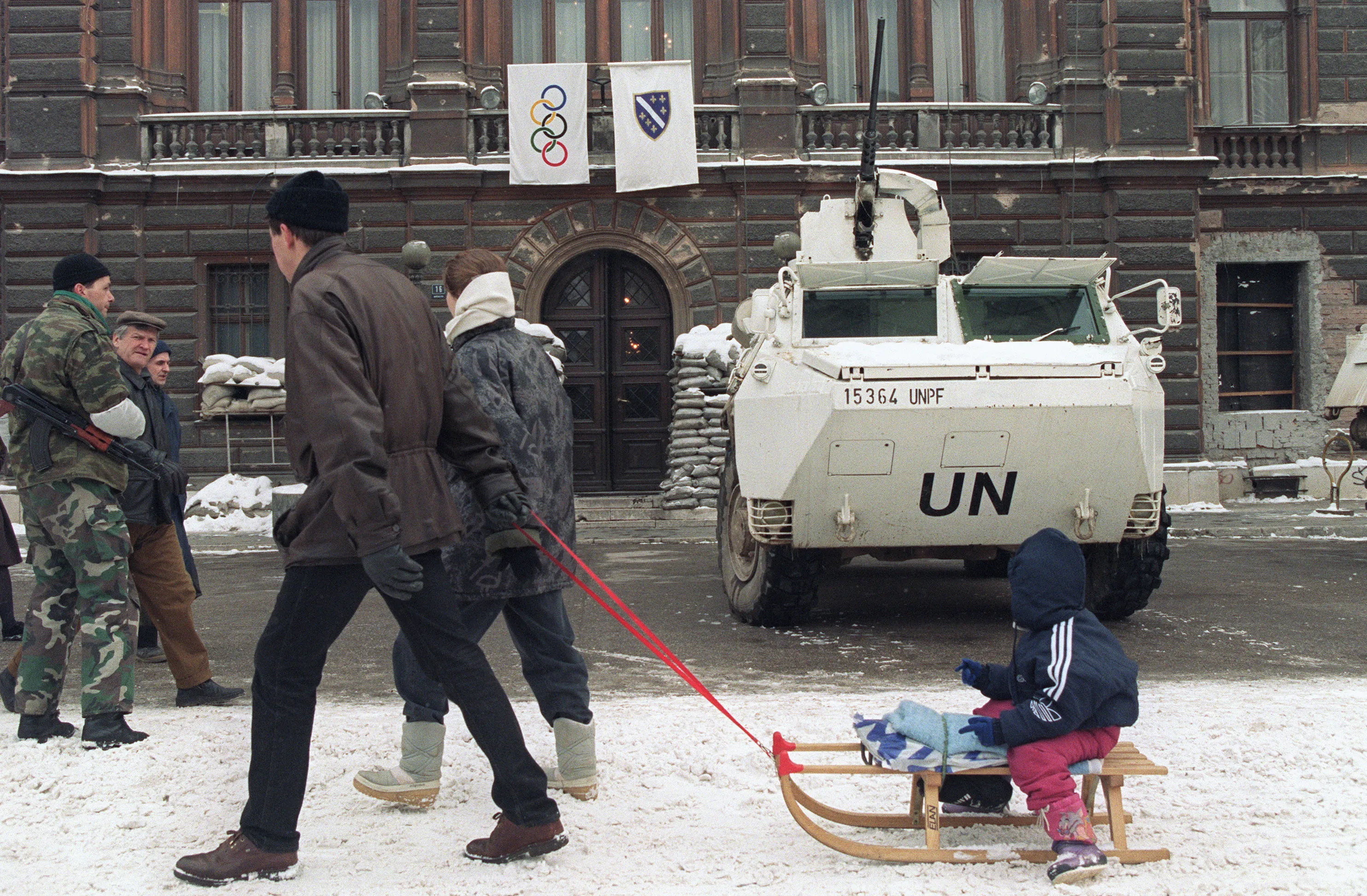 Two Bosnians pull a child on a toboggan on February 16, 1994 in front of th...