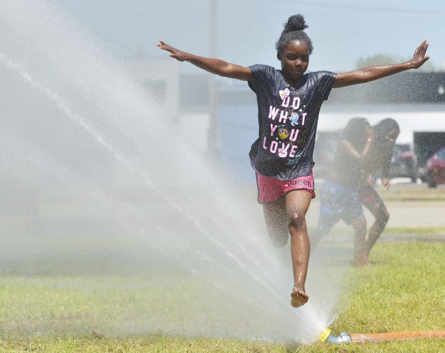 Serena Porter, 9, stays cool as she runs through water provided by the Benton Harbor Department of Public Safety during Spray and Play on Tuesday, June 18, 2024, at City Center Park in downtown Benton Harbor, Mich. (Photo by Don Campbell/The Herald-Palladium via AP Photo)