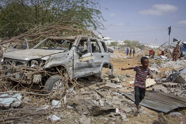 A young boy runs past the wreckage of a vehicle destroyed in an attack on police and checkpoints on the outskirts of the capital Mogadishu, Somalia Wednesday, February 16, 2022. The attack by the al-Shabab extremist group on Wednesday killed five people and wounded 16, police said. (Photo by Farah Abdi Warsameh/AP Photo)