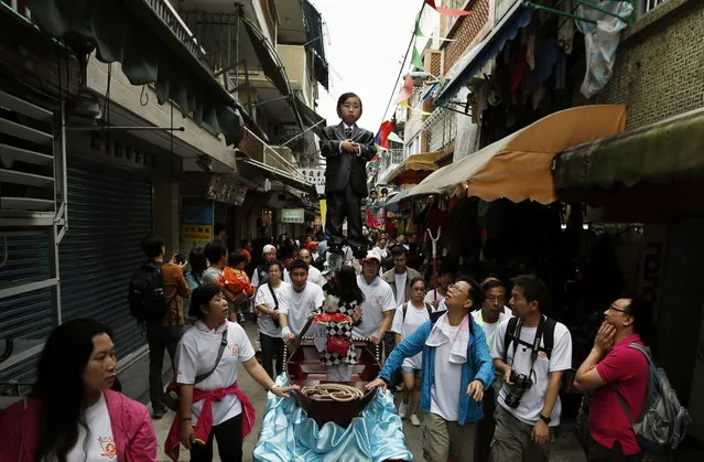 A girl dressed in a suit is supported by a hidden steel rod on a float at Hong Kong's Cheung Chau island during Bun Festival May 6, 2014. The festival celebrates the islanders' deliverance from famine many centuries ago and is meant to placate ghosts and restless spirits. (Photo by Bobby Yip/Reuters)