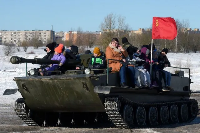 People ride on a military vehicle in an amusement park outside Gatchina, Leningrad region on March 6, 2022, as the part of celebration of Maslenitsa or Shrovetide, a farewell ceremony to winter. Shrovetide precedes the beginning of Lent, with each day of the week holding its own meaning. Shrove Sunday, also known as the Sunday of Forgiveness, is a day for asking forgiveness for the harm caused to other people intentionally or unintentionally. (Photo by AFP Photo/Stringer)