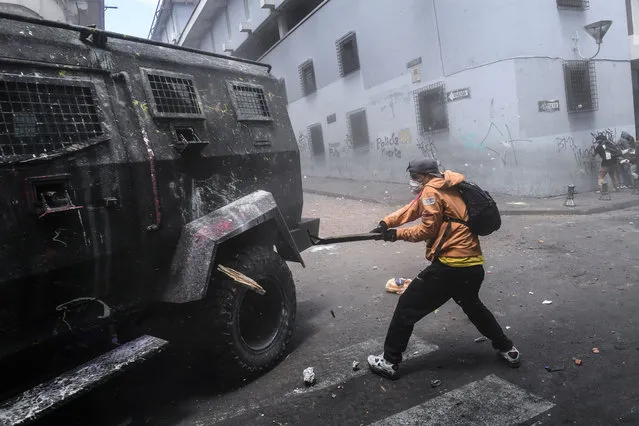 A demonstrator hits a riot police vehicle with a stick during clashes in Quito, as thousands march against Ecuadorean President Lenin Moreno's decision to slash fuel subsidies, on October 9, 2019. (Photo by Martin Bernetti/AFP Photo)