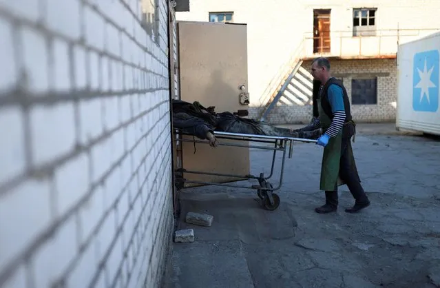 A worker carries the body of a civilian at a morgue, as Russia's invasion of Ukraine continues, in Mykolaiv, Ukraine on March 21, 2022. (Photo by Nacho Doce/Reuters)