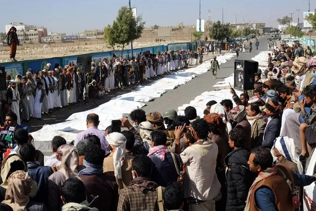 Onlookers gather as Yemenis pray during a mass funeral in Saada on January 25, 2022 for those killed in air strikes on a prison in in the northern Yemeni province on the weekend. The attack on the prison in rebel-held Saada, which was blamed on the Saudi-led coalition, left at least 70 people dead and wounded more than 100. The coalition, however, has denied bombing the prison. (Photo by AFP Photo/Stringer)