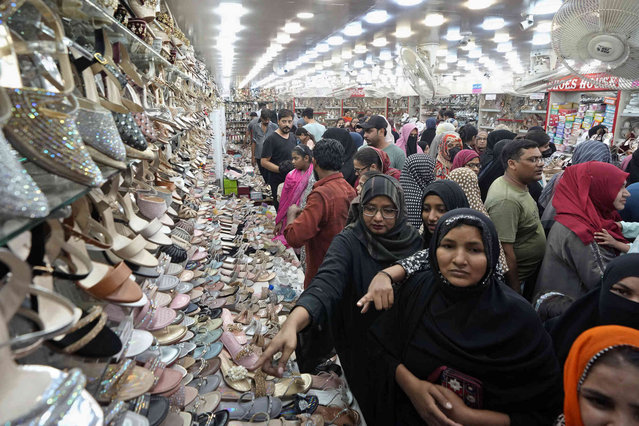 Women browse shoes while they visit a market to shop for the upcoming Eid al-Fitr celebrations, in Karachi, Pakistan, Wednesday, April 3, 2024. Eid al-Fitr marks the end of the Islamic holy month of Ramadan. (Photo by Fareed Khan/AP Photo)