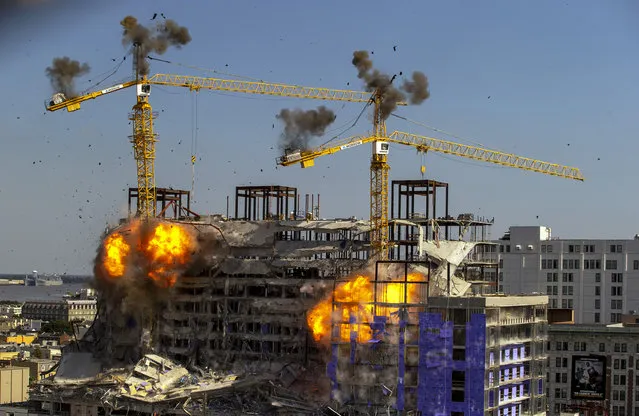 Two large cranes from the Hard Rock Hotel construction collapse come crashing down after being detonated for implosion in New Orleans, Sunday, October 20, 2019. Officials set off thundering explosions Sunday to topple two cranes looming precariously over a partially collapsed hotel in New Orleans, but most of one crane appeared to be left dangling atop the ruined building while the other crashed down. (Photo by David Grunfeld/The Advocate via AP Photo)