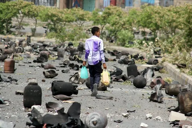 A boy walks on a street littered with cooking gas cylinders after a fire and explosions destroyed a nearby gas storage during clashes between fighters of the Popular Resistance Committees and Houthi fighters earlier today, in Yemen's southwestern city of Taiz July 19, 2015. (Photo by Reuters/Stringer)