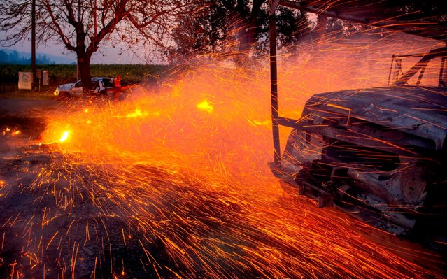 In this file photo taken on October 27, 2019 fire and embers blow around a burnt utility truck during the Kincade fire in Healdsburg, California. California's governor declared a statewide emergency on October 27, 2019 as a huge blaze, fanned by strong winds, forced mass evacuations and power blackouts as it bore down on towns in the famed Sonoma wine region.The so-called Kincade Fire, north of San Francisco, has spread to 30,000 acres (12,000 hectares) and was only 10 percent contained by Sunday evening, state fire authorities said. (Photo by Josh Edelson/AFP Photo)