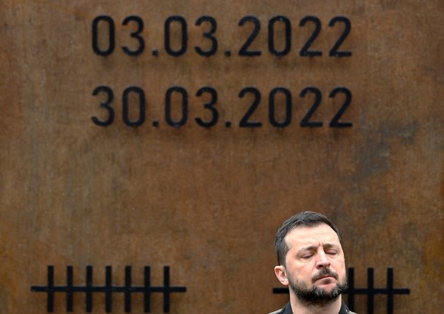 Ukrainian President Volodymyr Zelensky reflects in front of a memorial plaque outside the school in the village of Yahidne, Chernihiv region, in the basement of which the residents were jailed during the Russian occupation on April 3, 2023 during a visit to mark the first anniversary of the village liberation, amid the Russian invasion of Ukraine. (Photo by Sergei Supinsky/AFP Photo)