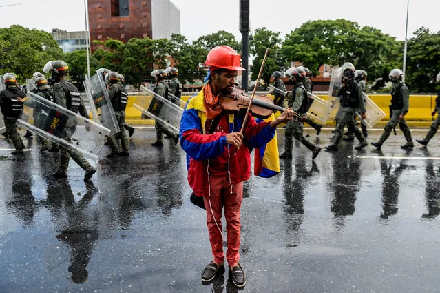 An opposition demonstrator plays the violin during a protest against President Nicolas Maduro in Caracas, on May 24, 2017. Venezuela' s President Nicolas Maduro formally launched moves to rewrite the constitution on Tuesday, defying opponents who accuse him of clinging to power in a political crisis that has prompted deadly unrest. (Photo by Federico Parra/AFP Photo)