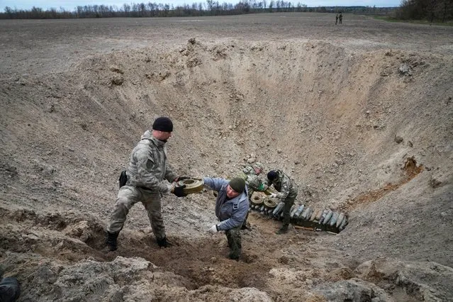 Interior ministry sappers collect explosives in a hole to detonate them near a mine field after recent battles at the village of Moshchun close to Kyiv, Ukraine, Tuesday, April 19, 2022. (Photo by Efrem Lukatsky/AP Photo)
