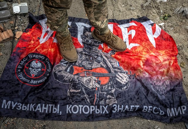 A Ukrainian serviceman stands on a flag of Russia's mercenary group Wagner near the Russian border in Sumy region, Ukraine on August 13, 2024. (Photo by Viacheslav Ratynskyi/Reuters)