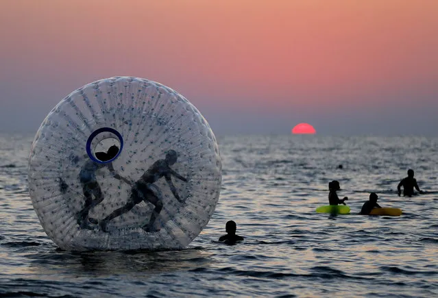 People watch the sunset at the Black Sea beach of the seaside resort of Urek, Georgia, 28 July 2015. The Black Sea resorts are a popular destination for summer vacations. (Photo by Zurab Kurtsikidze/EPA)