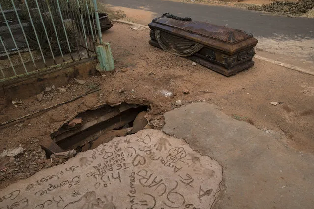 An oxidized coffin lies next to a grave that was dug up by thieves at “Corazon de Jesus” cemetery, or Heart of Jesus cemetery, in Maracaibo, Venezuela, November 21, 2019. Thieves often raid graves for valuables, while public cemeteries often go abandoned, overgrown with weeds. (Photo by Rodrigo Abd/AP Photo)