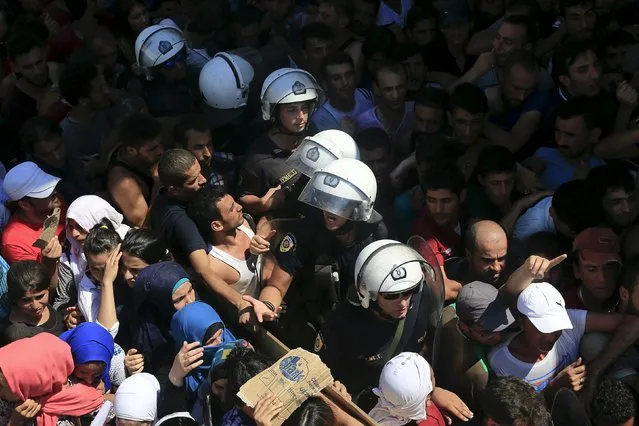 Riot police move through a crowd of migrants and refugees during a registration procedure at the national stadium of the Greek island of Kos, August 12, 2015. (Photo by Alkis Konstantinidis/Reuters)
