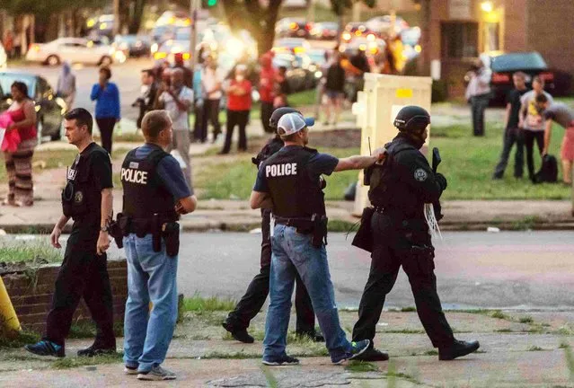 Police monitor the crowd as protesters gathered after a shooting incident in St. Louis, Missouri August 19, 2015. (Photo by Kenny Bahr/Reuters)