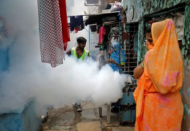 Women cover their faces as a health worker fumigates a residential neighbourhood during a drive to prevent the spread of mosquito-borne diseases following recent rainfall and water logging, in Ahmedabad, India on July 20, 2022. (Photo by Amit Dave/Reuters)