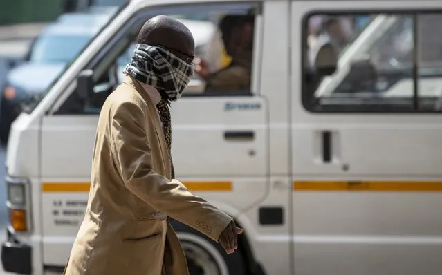 A man using a scarf to cover his face walks along a downtown street Johannesburg, South Africa, Monday, March 16, 2020. South African President Cyril Ramaphosa declared a national state of disaster. Ramaphosa said all schools will be closed for 30 days from Wednesday and he banned all public gatherings of more than 100 people. South Africa will close 35 of its 53 land borders and will intensify screening at its international airports. For most people, the new COVID-19 coronavirus causes only mild or moderate symptoms. For some it can cause more severe illness. (Photo by Themba Hadebe/AP Photo)