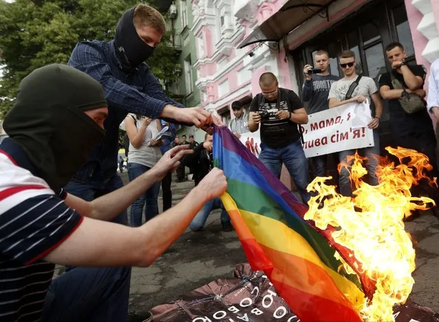 Anti-LGBT protesters burn an LGBT flag at the International Amnesty building during the opening ceremony of the Pride Week in Kyiv, Ukraine, Tuesday, June 13, 2017. Despite the war in Ukraine, the country's largest LGBT rights event, KyivPride, is going ahead on Saturday, June 25, 2022. But not on its native streets and not as a celebration of gay pride. It will instead join Warsaw's yearly Equality Parade, using it as a platform to keep international attention focused on the Ukrainian struggle for freedom. (Photo by Sergei Chuzavkov/AP Photo/File)