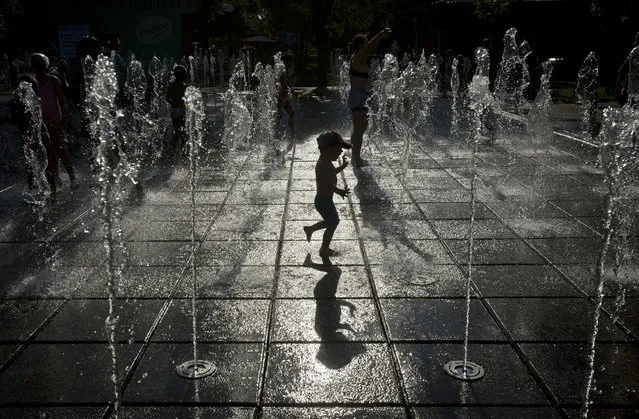 A child plays in a fountain, in Bucharest, Romania, Thursday, August 14, 2014. Romania's weather authority issued a heat wave warning until the weekend with temperatures expected to exceed 37 degrees Celsius (98.6 degrees Fahrenheit) in many regions of the country. (Photo by Vadim Ghirda/AP Photo)