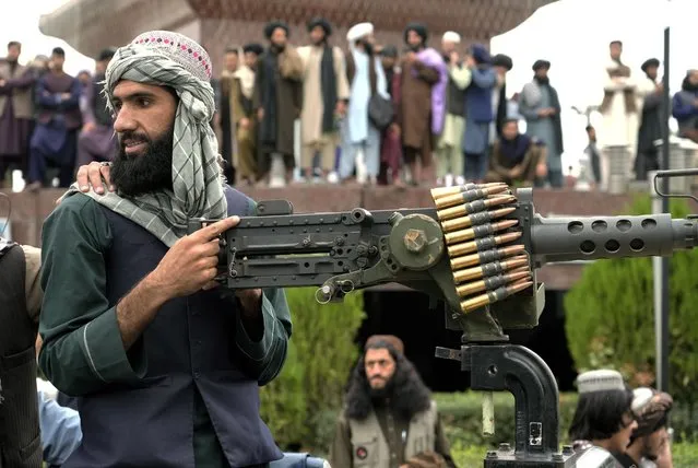 A Taliban fighter mans his weapon during celebrations one year after the Taliban seized the Afghan capital, Kabul, in front of the U.S. Embassy in Kabul, Afghanistan, Monday, August 15, 2022. The Taliban marked the first-year anniversary of their takeover after the country's western-backed government fled and the Afghan military crumbled in the face of the insurgents' advance. (Photo by Ebrahim Noroozi/AP Photo)
