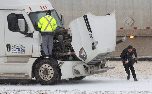 Truckers fight the weather as they stop on Interstate 44 in Fenton, Mo. to change wiper blades as sleet falls on Sunday, January 5, 2025. (Photo by Robert Cohen/St. Louis Post-Dispatch via AP Photo)