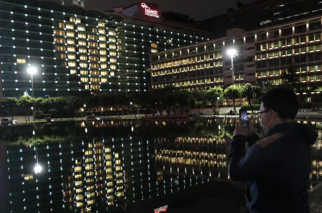 A man uses his mobile phone to take photos of Hotel Indonesia Kempinski, where room lights make the shape of a heart to honor healthcare and other essential workers still on the job, during the new coronavirus outbreak in Jakarta, Indonesia, Friday, April 17, 2020. Indonesia's capital kicked off a stricter restriction to slow the spread of the new coronavirus last week as the metropolitan area has become Indonesia's coronavirus epicenter. (Photo by Dita Alangkara/AP Photo)