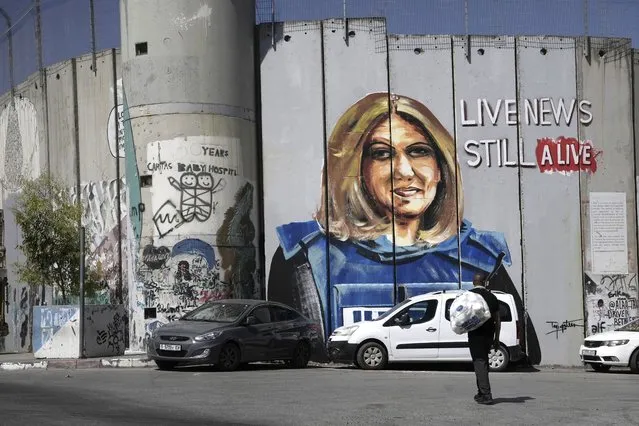 A man walks near a mural depicting slain Palestinian American journalist Shireen Abu Akleh, on Israel's controversial separation barrier in the West Bank city of Bethlehem, Wednesday, July 6, 2022. The mural by Palestinian artist Taqi Spateen appeared early Wednesday, days ahead of a visit by U.S. President Joe Biden. (Photo by Mahmoud Illean/AP Photo)