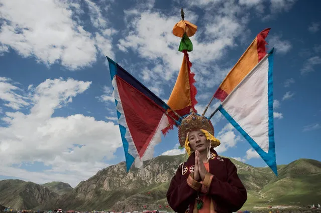 This picture taken on July 25, 2016 shows a Tibetan Buddhist monk with an elaborate headdress posing for a photo at a local festival in Yushu, in the northwestern Chinese province of Qinghai. The festival held since the 1990s lasts for around five days. It was suspended for several years following a 2010 earthquake in Yushu which killed some 2,700 people. (Photo by Nicolas Asfouri/AFP Photo)