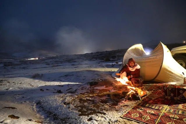 A man sits beside a tent after snowfall in Tabuk, Saudi Arabia, February 25, 2020. (Photo by Mohamed Al Sultan/Reuters)