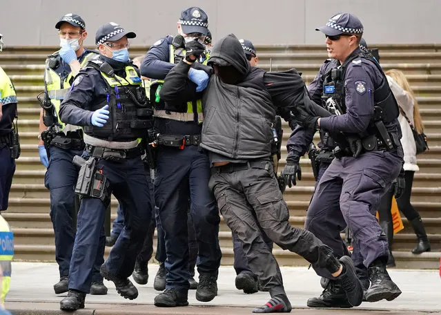 Police officers detain a protester opposing lockdown measures implemented to curb the spread of the coronavirus disease (COVID-19) outside Parliament House in Melbourne, Australia, May 10, 2020. (Photo by Scott Barbour/AAP Image via Reuters)