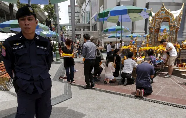 A Thai police officer stands guard as people pray at the Erawan shrine in central Bangkok, Thailand, September 8, 2015. An August 17 attack on the Erawan shrine killed 20 people and injured more than 100. (Photo by Chaiwat Subprasom/Reuters)