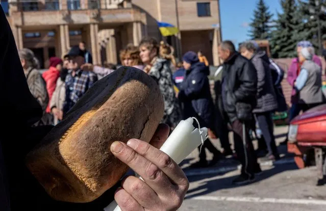 Locals wait in line for bread, candles and food provided by aid workers as there is no electricity in Balakliia, recently liberated by Ukrainian Armed Forces, amid Russia's invasion of Ukraine, in Kharkiv region, Ukraine on September 21, 2022. (Photo by Umit Bektas/Reuters)