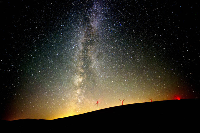 The Milky Way lights up the Pacific Northwest sky during the Perseid Meteor Shower Friday morning, Aug. 12, 2016 by the wind mills located north of Dayton, Wash. (Photo by Michael Lopez/Walla Walla Union-Bulletin via AP Photo)