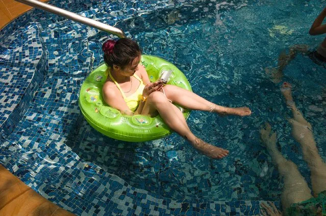 In this picture taken on July 25, 2016, a woman looks at her smartphone while sitting in a inflatable ring in a pool in Chengdu in Sichuan province. China had 1.3 billion mobile users by the end of 2015, and nearly 30 percent of them – a swathe of humanity larger than the whole population of the United States – were connected to the 4G network, according to its ministry of industry and information technology. (Photo by Fred Dufour/AFP Photo)