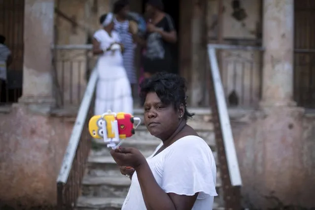 Coffeeshop worker Yudi Linares, 37, takes a selfie during the party of Yensy Villarreal, 9, (not pictured), in celebration for becoming a Santero after passing a year-long rite of passage in the Afro-Cuban religion Santeria, Havana, July 5, 2015. (Photo by Alexandre Meneghini/Reuters)